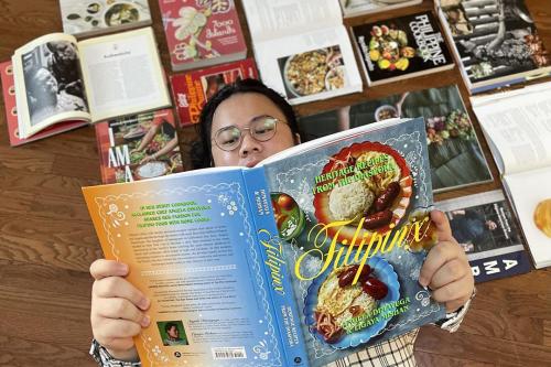 A person reading a magazine surrounded by journal and book covers